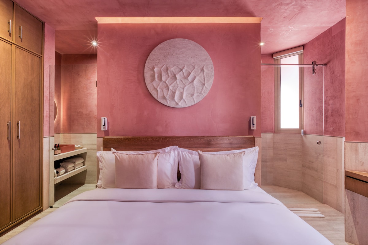 Ein Schlafzimmer mit einem Holzkopfende, einer runden Wanddekoration und einer eingebauten Ablage mit Handtüchern.