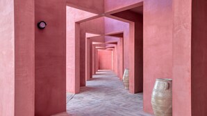Un pasillo con paredes rosas y suelo de espiga, que conduce a un barril grande.