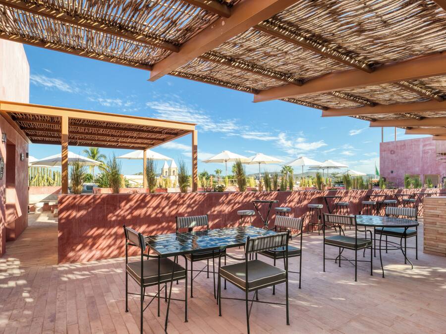 An outdoor patio area with tables and chairs, a pergola, and umbrellas.