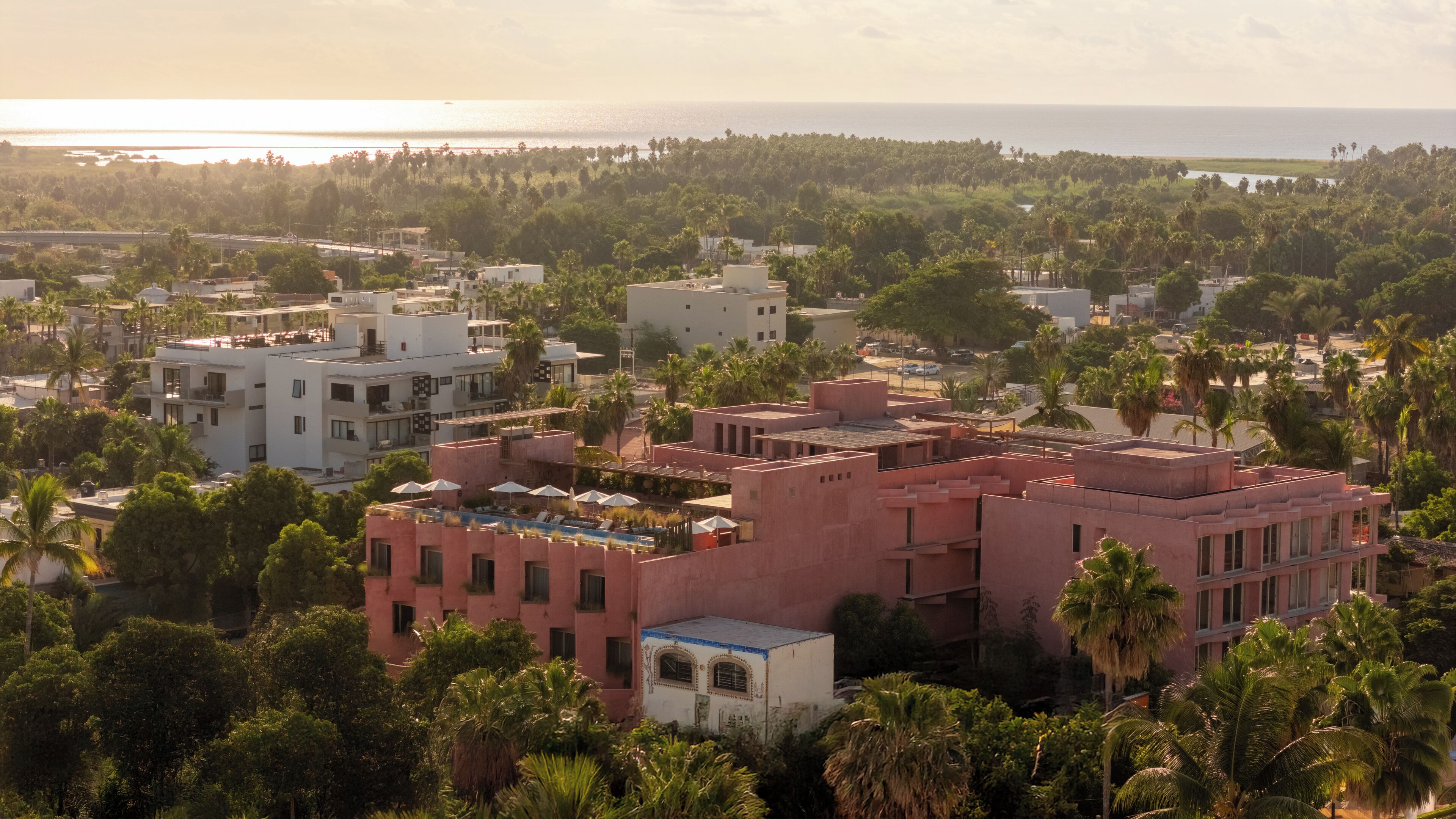A coastal residential area with modern buildings, a swimming pool, and dense greenery.