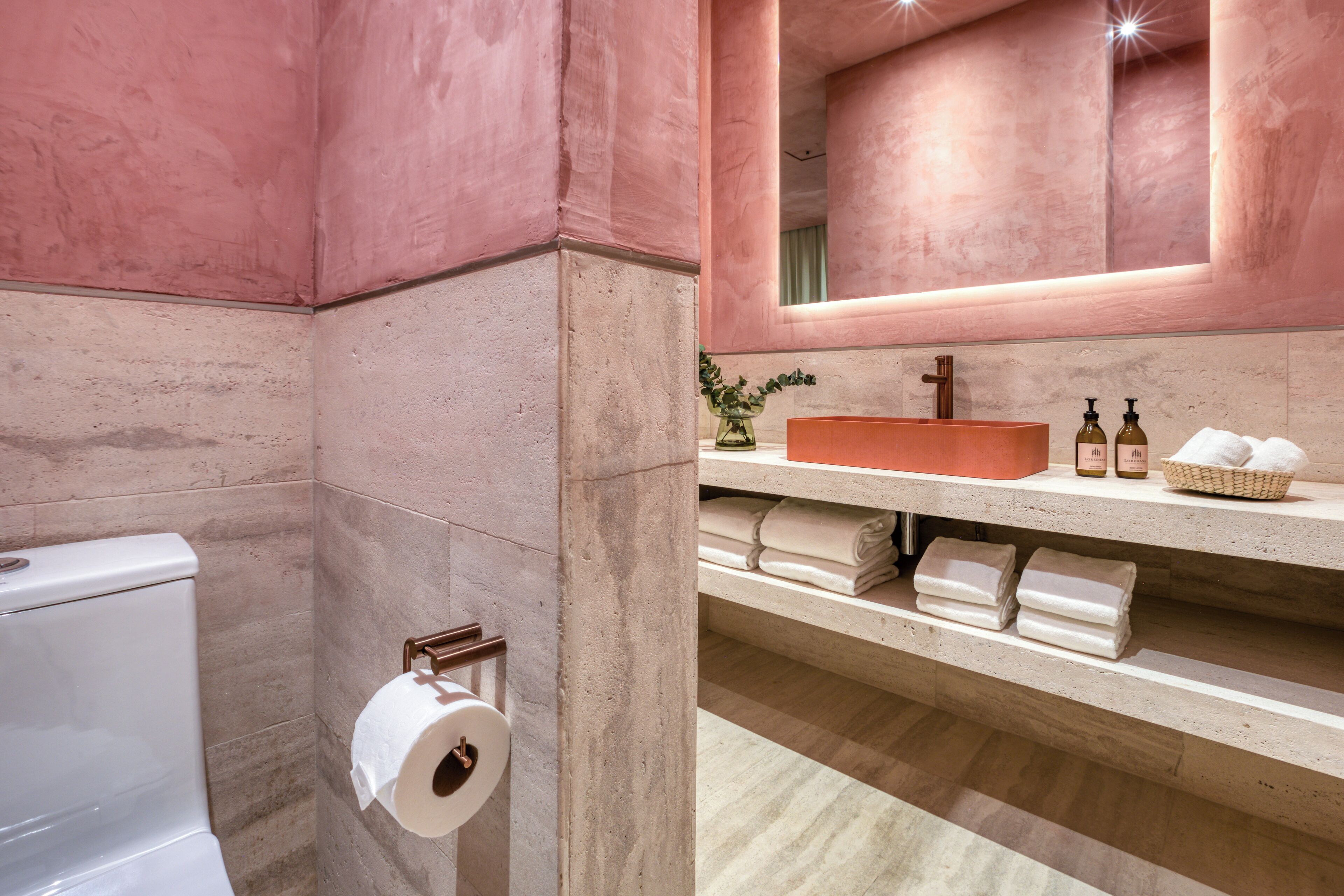 A bathroom with a toilet, a sink with a mirror, and a towel rack.