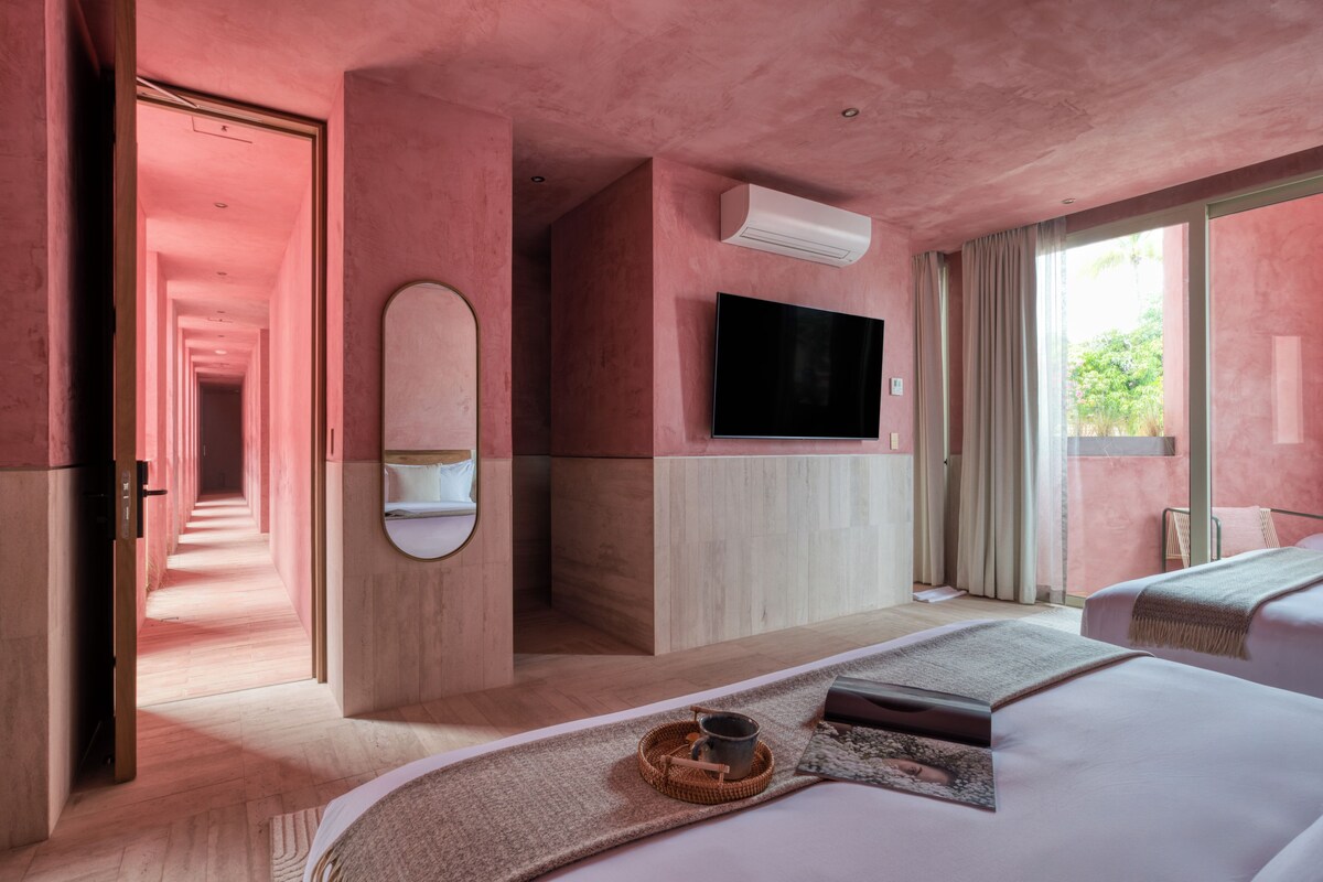 Een moderne hotelkamer met een groot bed, een flatscreen televisie, een spiegel en uitzicht op het omliggende landschap.
