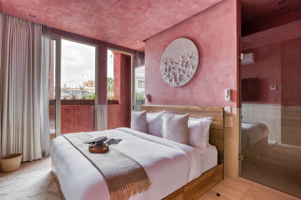 Een moderne hotelkamer met een groot bed, een ronde wandversiering en uitzicht op de stad door een glazen deur.