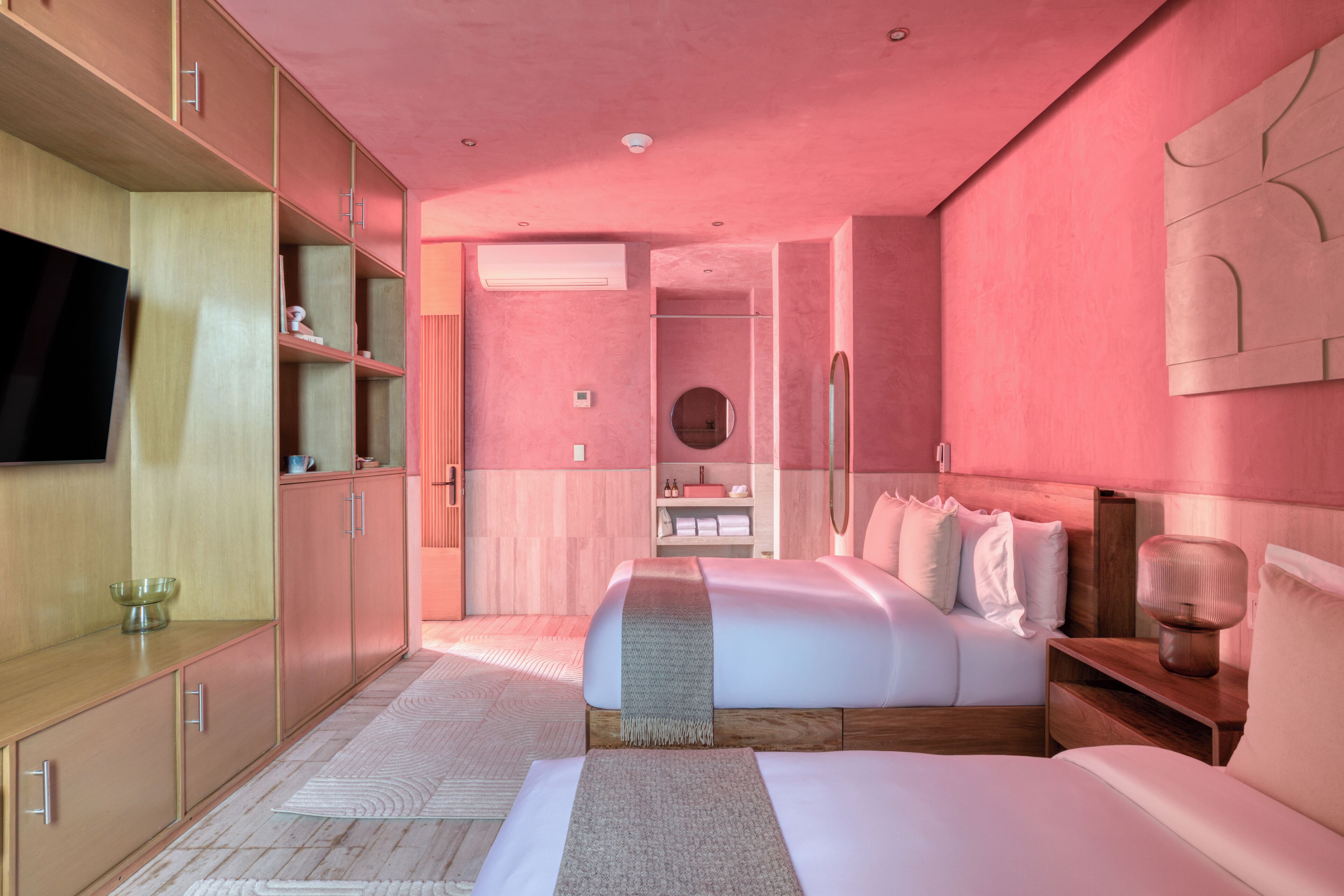 Un dormitorio moderno con una cama grande, televisión y almacenamiento integrado.
