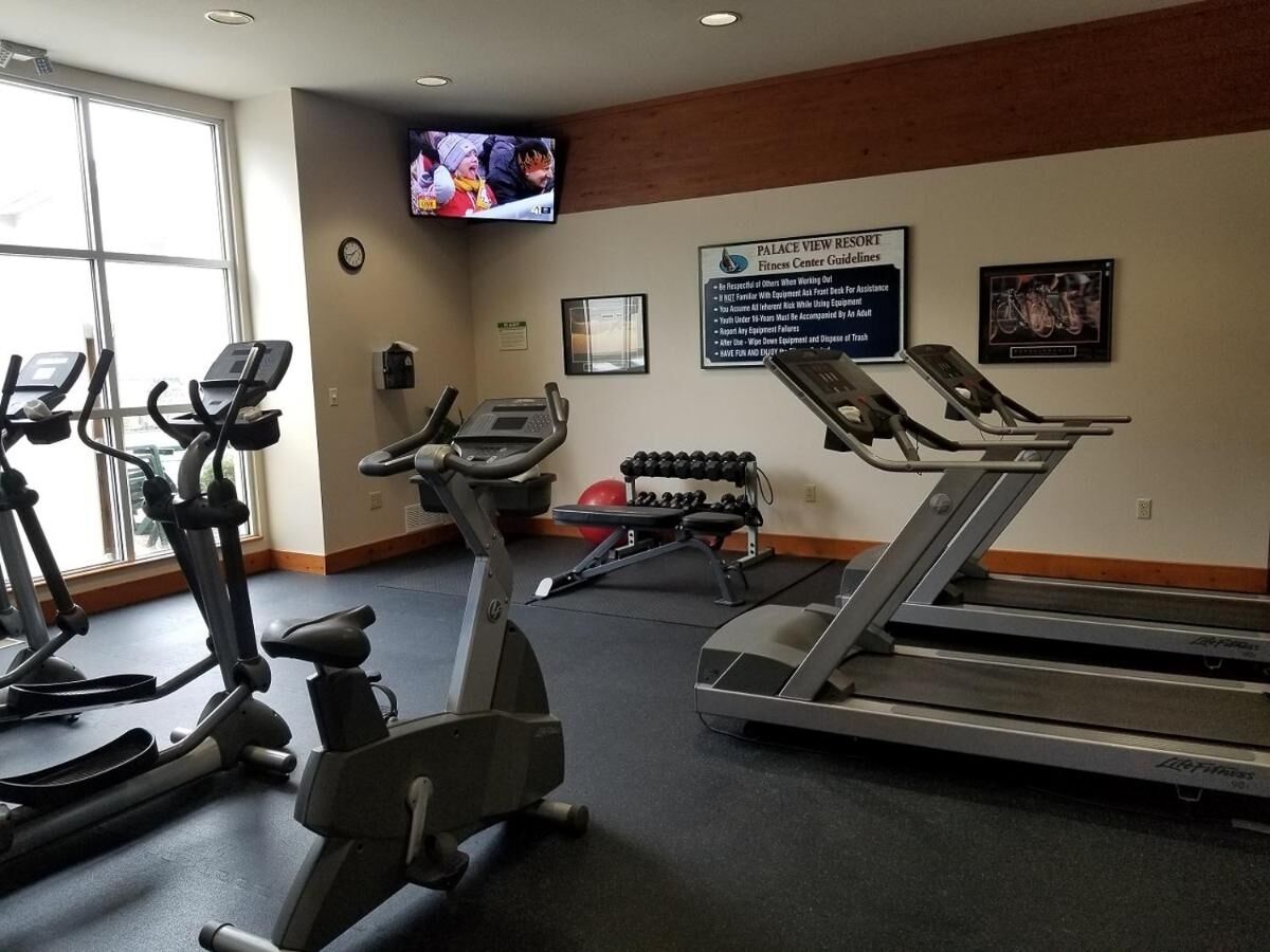 Un centre de remise en forme équipé de tapis de course, de vélos elliptiques et d’un écran de télévision diffusant une émission.