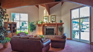 A spacious living room with a fireplace, leather sofas, and large windows offering a view of the outdoors. - 2BR w/ Full Kitchen Near Branson Strip – Perfect for Group Getaways | 2 Units (Branson)