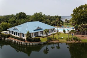 Una casa grande con techo azul, piscina y muelle que se extiende sobre un lago.