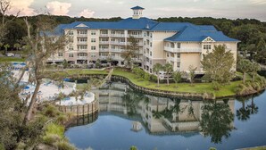 A large hotel with multiple balconies, a central courtyard, and a lake.