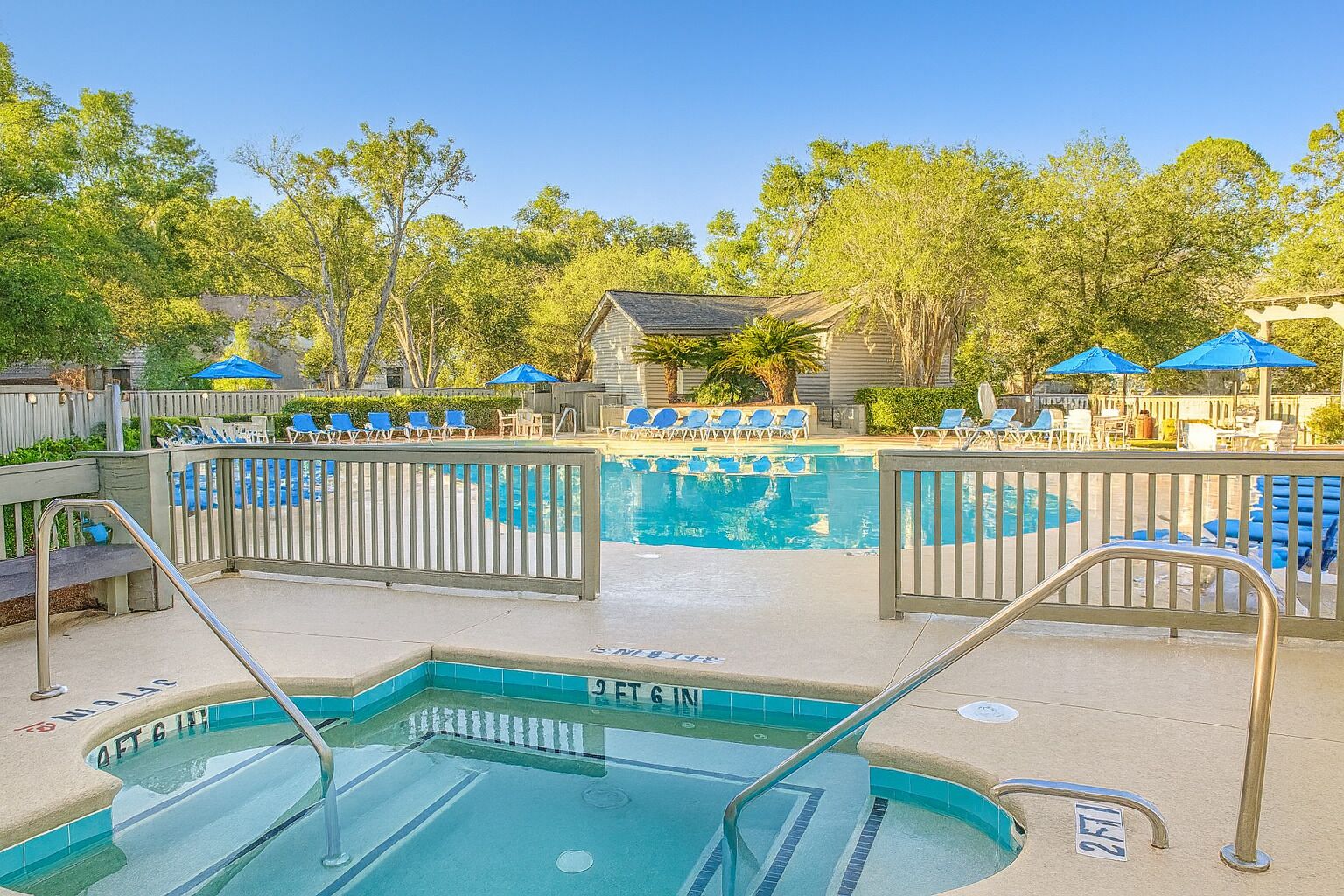 A swimming pool with a wooden deck, lounge chairs, and umbrellas.