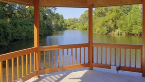 Una terraza de madera con vista a un río rodeado de árboles.