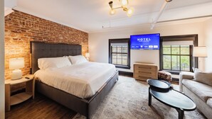 Camera d'albergo con parete in mattoni, un letto grande, una TV e vista all'aperto.