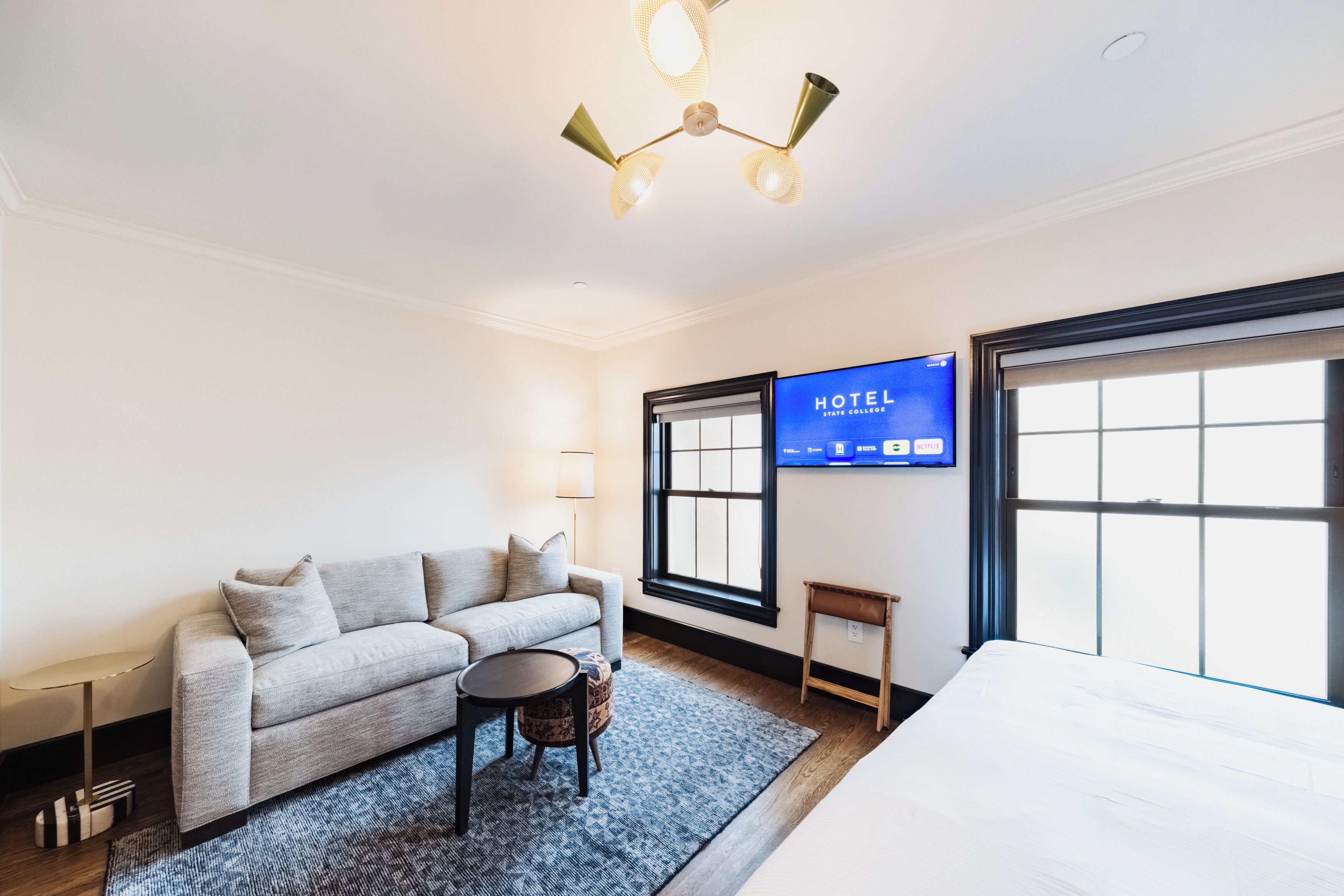 A hotel room with a bed, a sofa, a small table, a TV, and a window.