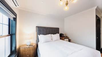 Habitación de hotel con una cama grande, una mesita de noche con lámpara, y un ventilador de techo.