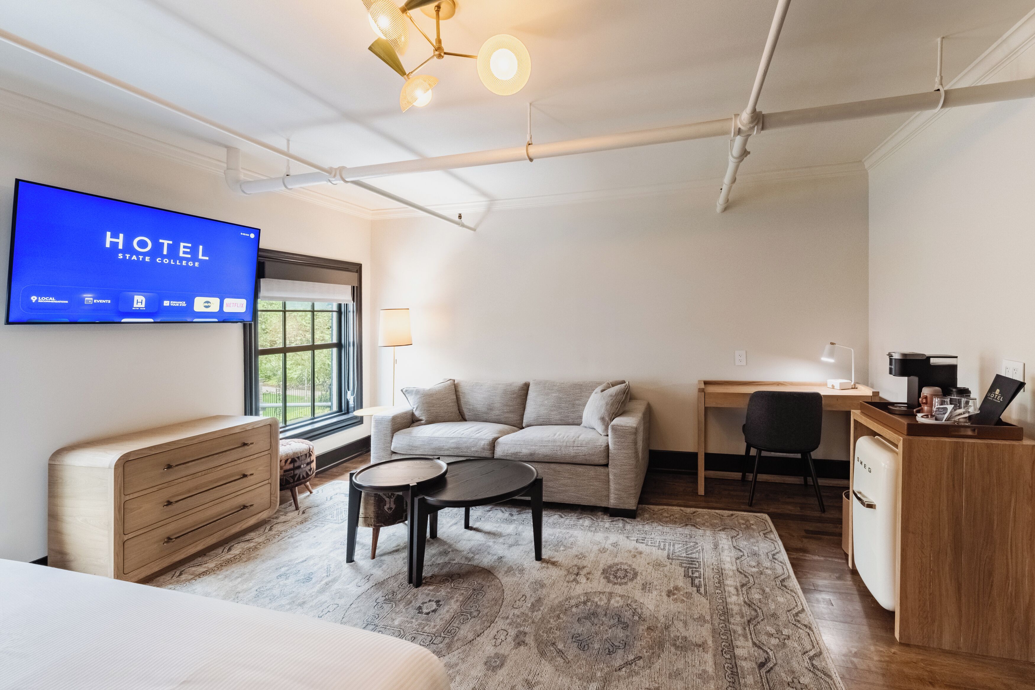 Une chambre d’hôtel équipée d’un lit, d’un bureau, d’un canapé, d’une télévision et d’une machine à café.