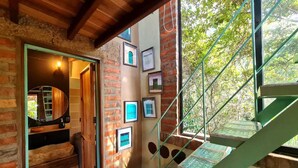A staircase with glass steps leading to a balcony, surrounded by brick walls and framed pictures. - La Casita Del Bosque, a mini-hut surrounded by native forest (Barichara)