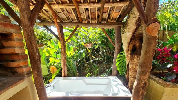 A hot tub under a wooden pergola surrounded by lush greenery. - La Casita Del Bosque, a mini-hut surrounded by native forest (Barichara)