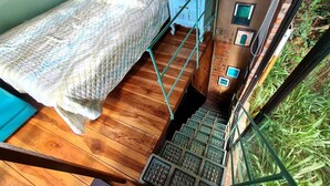 A bedroom with a bed, a small table, and a staircase leading to an outdoor area. - La Casita Del Bosque, a mini-hut surrounded by native forest (Barichara)