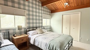 A bedroom with a checkered wall, a bed, a nightstand, a lamp, and a window with blinds. - Hilltop's Cozy Cabin with Lakeviews, close to beach. Pet friendly (Windermere)