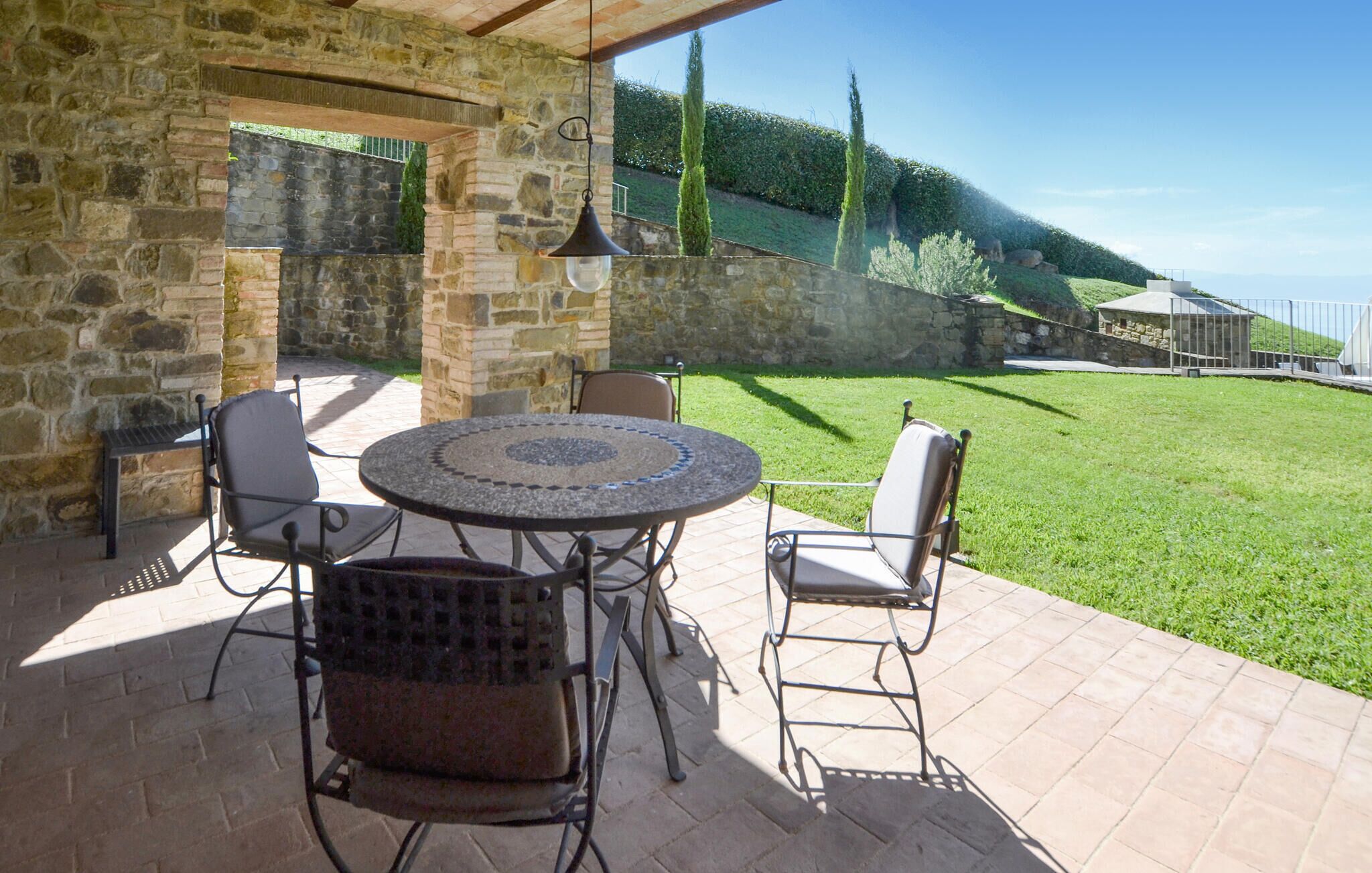 An outdoor patio with stone walls, a round table, and four chairs.