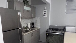 Cocina compacta con refrigerador, estufa y pileta.