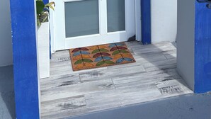 Una puerta blanca con un panel de vidrio esmerilado y un candado electrónico, además de un pequeño cartel de bienvenida arriba.