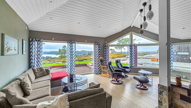 A spacious living room with a large window offering a scenic view, a comfortable sofa, and a modern chair. - Beautiful home in Fitjar with house sea view (Fitjar)