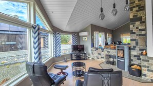 A modern living room with a stone fireplace, leather seating, and a TV. - Beautiful home in Fitjar with house sea view (Fitjar)