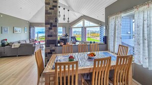 A dining area with a wooden table and chairs, a sofa, and a stone pillar. - Beautiful home in Fitjar with house sea view (Fitjar)