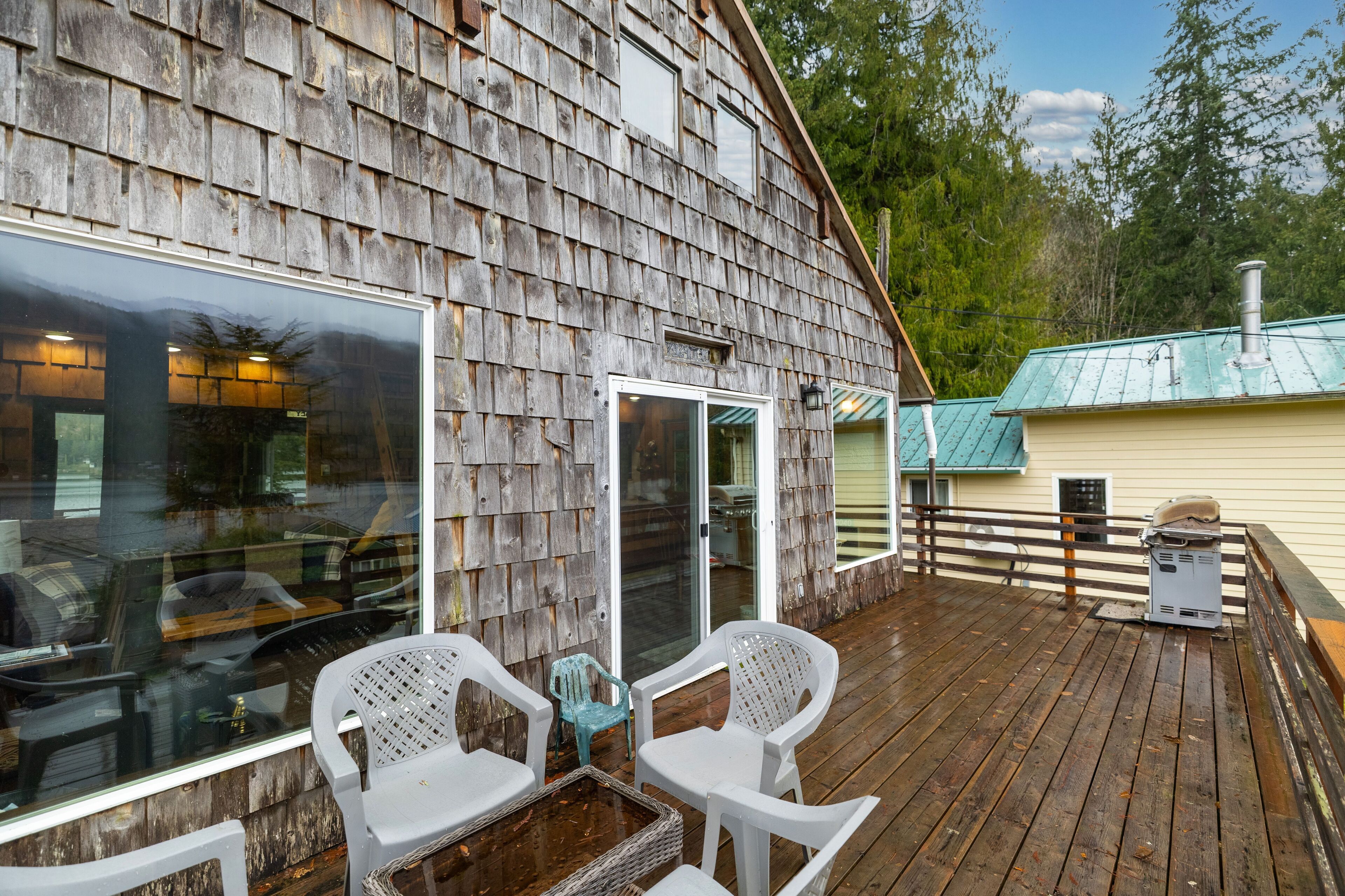A wooden deck with a table and chairs, a glass door, and a metal heater.