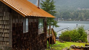 A wooden cabin with a metal roof overlooking a lake and forested mountains. - Lake Sutherland Cabin w/ Dock Access & Kayaks (Port Angeles)