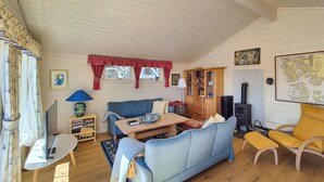 A cozy living room with a blue sofa, a wooden coffee table, a map on the wall, and a wood-burning stove.