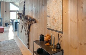A room with a wooden wall, a map, a table with a sculpture, and a fur rug.