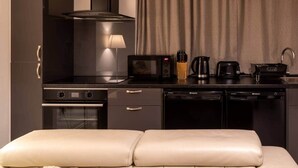 A compact kitchen with a stove, microwave, and coffee maker. There is a dining area with a cushioned bench. - Luxury modern flat • close to city • free parking (Leeds)