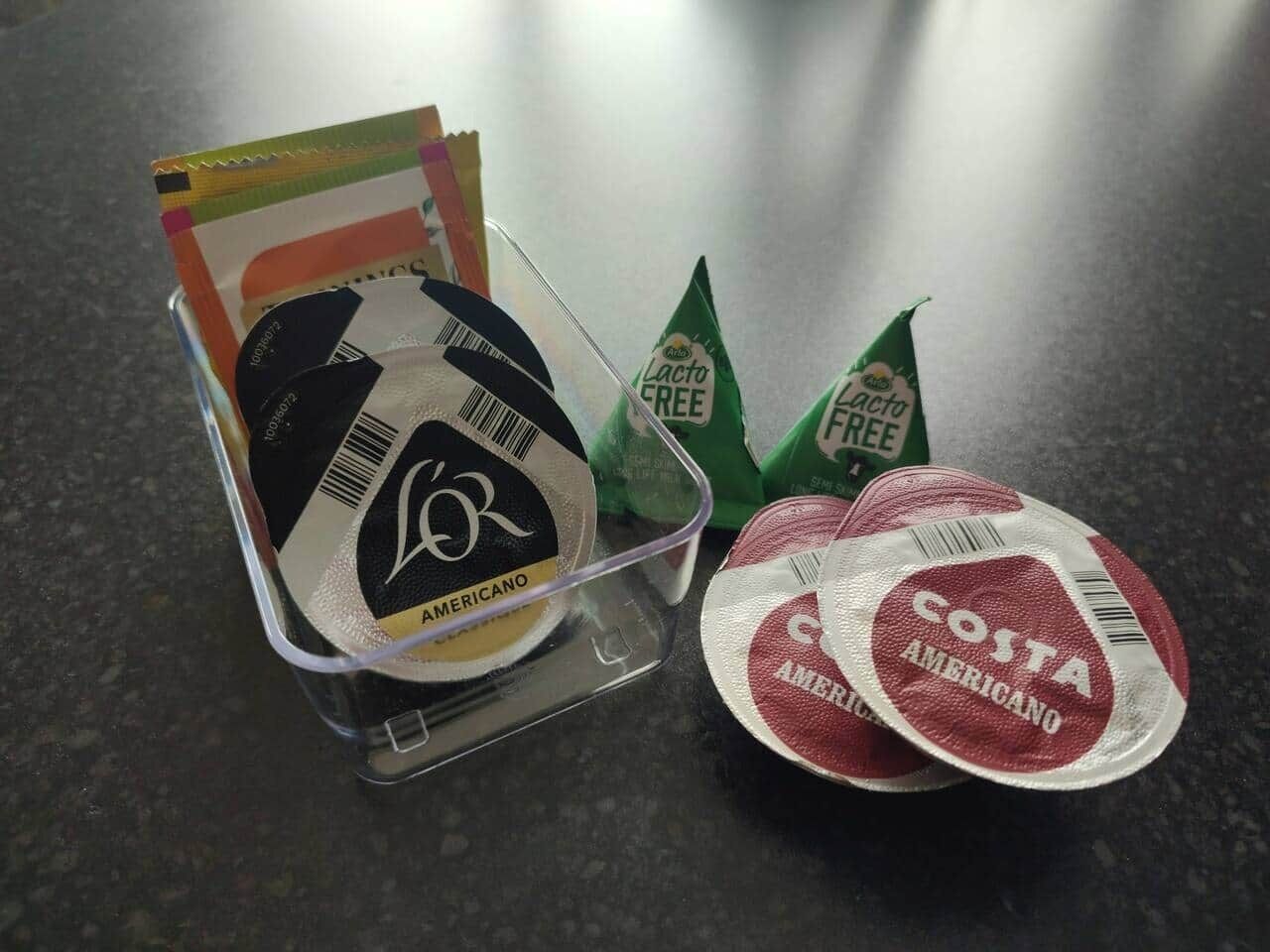 A plastic container with a black lid, a green label, and a red and white label with the text "COSTA AMERICANO".