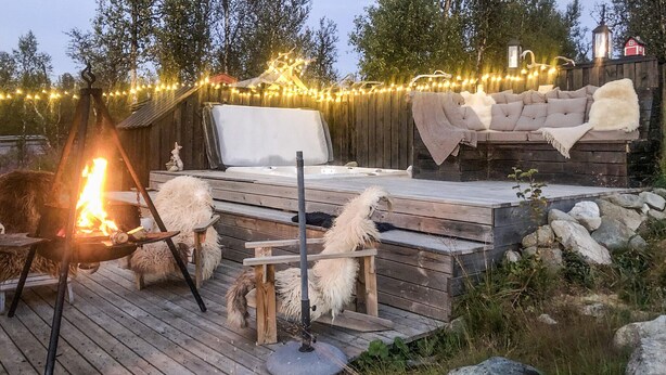 Eine Terrassenausstattung im Freien mit Feuerstelle, einer Sitzecke und Lichterketten.