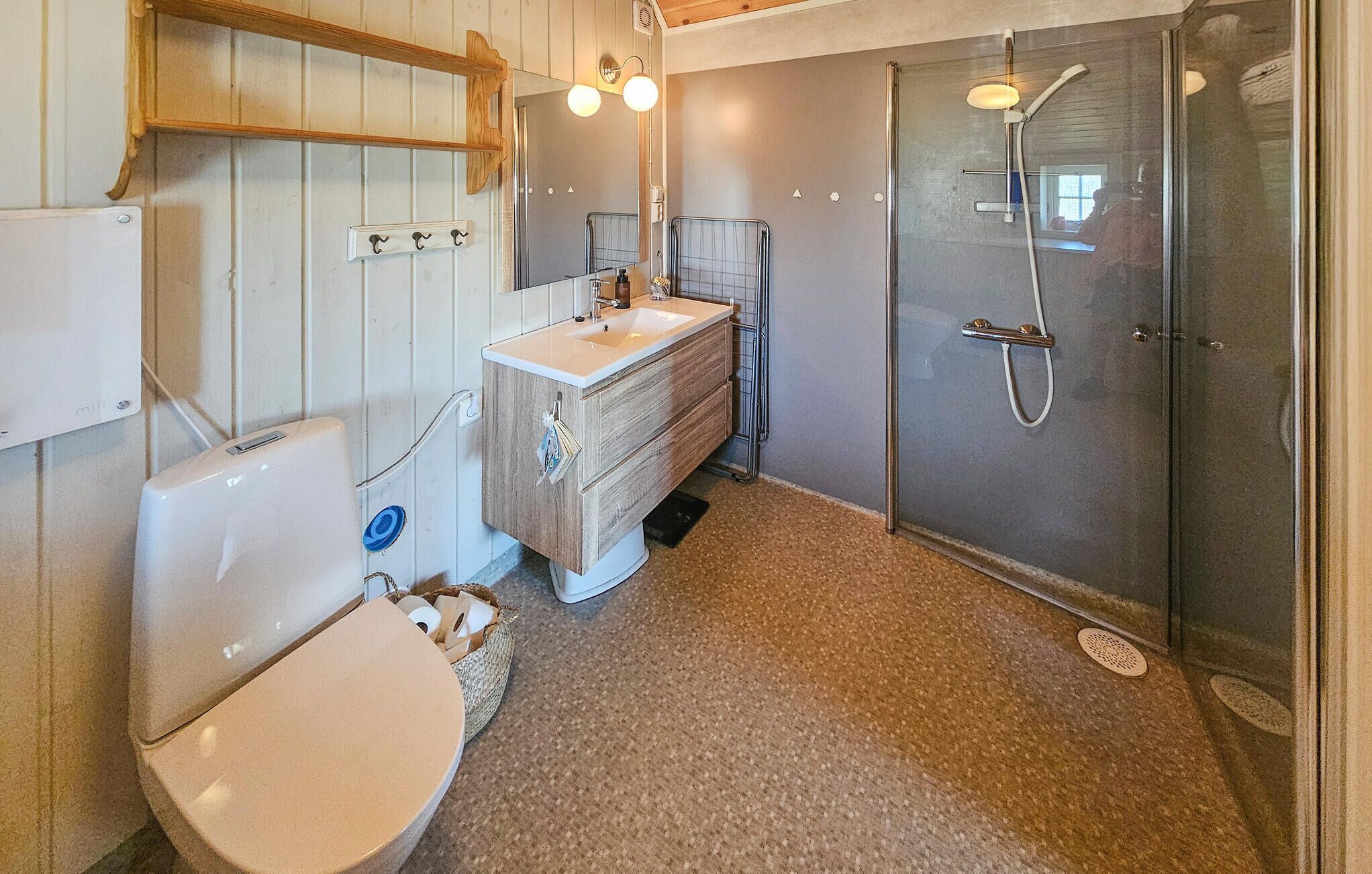 Et badeværelse med toilet, vask og brusebad.