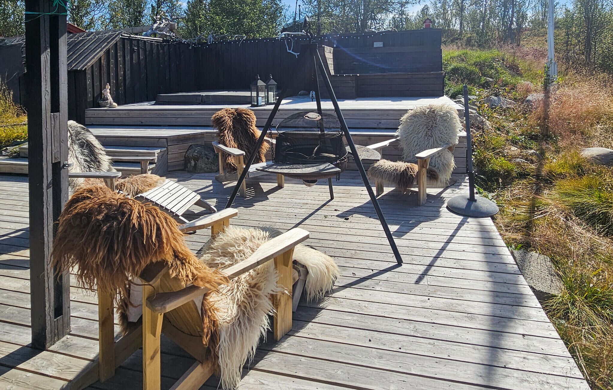 En träveranda med rustika stolar och en gunga.