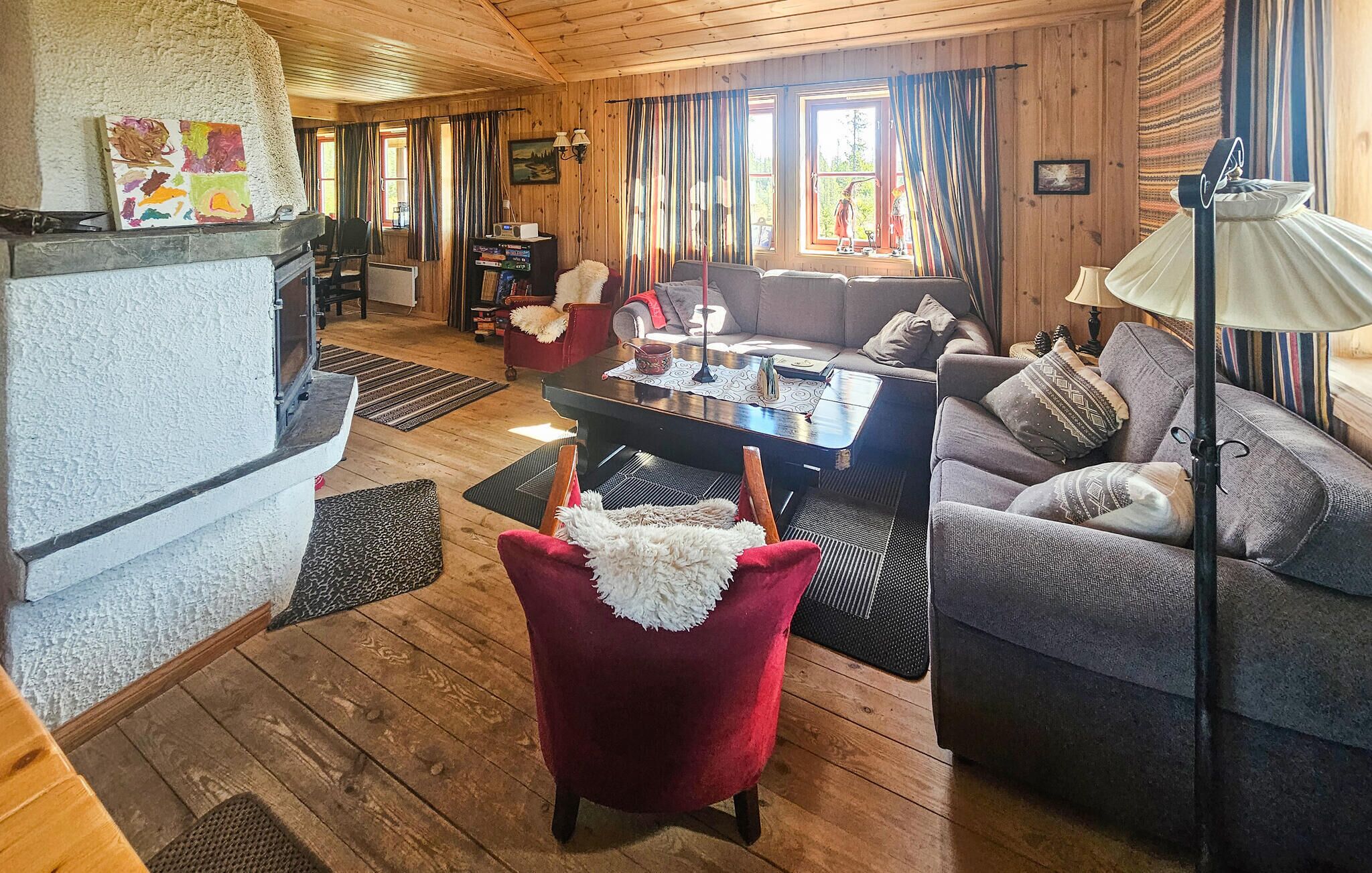 A cozy cabin interior with a fireplace, a dining area, and a living room with a sofa and armchairs.