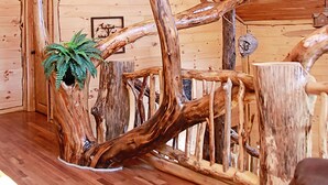 Ein Zimmer mit Holzboden und -wänden, das einen großen Baumstumpf als Mittelpunkt und eine kleine Pflanze beherbergt.