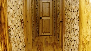 Ein schmaler Korridor mit Holzboden und Wänden, die mit einem steinartigen Material verkleidet sind.