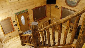 Ein Holzblock-Innenraum mit einer Wendeltreppe, Holzwänden und einem an der Wand befestigten Fernseher.