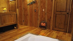 Ein Holzinnenraum mit einer Badewanne, einem kleinen Heizgerät und Holztüren.