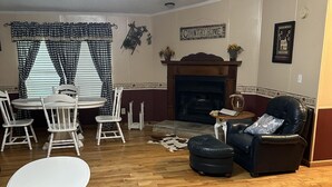 A living room with a fireplace, a dining table with chairs, a sofa, and a cowhide rug. - Creek Side Retreat (Chapmanville)