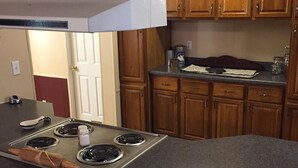 A kitchen with wooden cabinets, a stainless steel stove, and a countertop. - Creek Side Retreat (Chapmanville)
