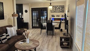 Ein modernes Wohnzimmer mit einem braunen Sofa, einem Couchtisch und einem Essbereich mit einer Chandeliebre.