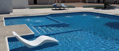 En swimmingpool med vandrutsjebaner, liggestole og et palmetræ.