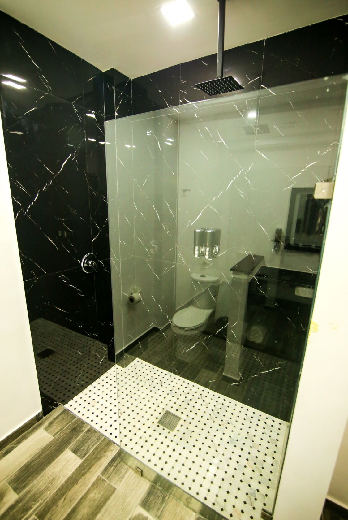 Et moderne badeværelse med glasvæg, toilet og vask.