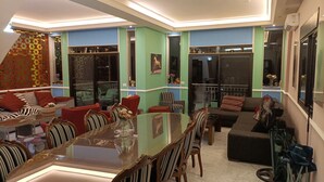 Ein modernes Wohnzimmer mit Essbereich, ausgestattet mit einem Glastisch, gestreiften Stühlen sowie einer Kombination aus Sofas und Sesseln.