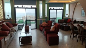 Ein geräumiges Wohnzimmer mit Balkon, grünen Wänden und Blick auf die Stadt.