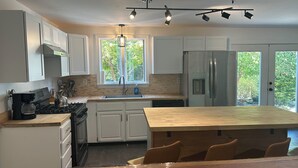 Una cocina moderna con armarios blancos, un refrigerador de acero inoxidable, un horno empotrado y una isla grande con taburetes de bar.